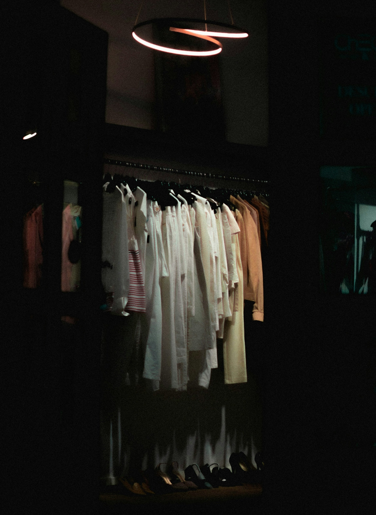 a rack of clothes in a dark room