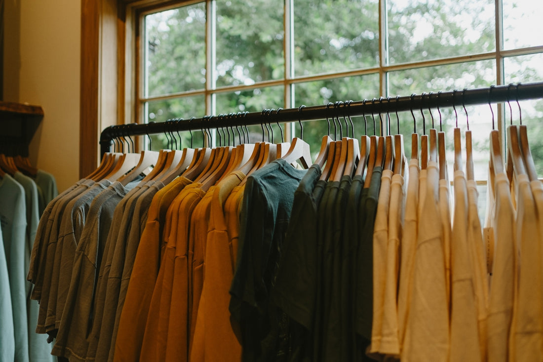 a rack of shirts hanging in front of a window