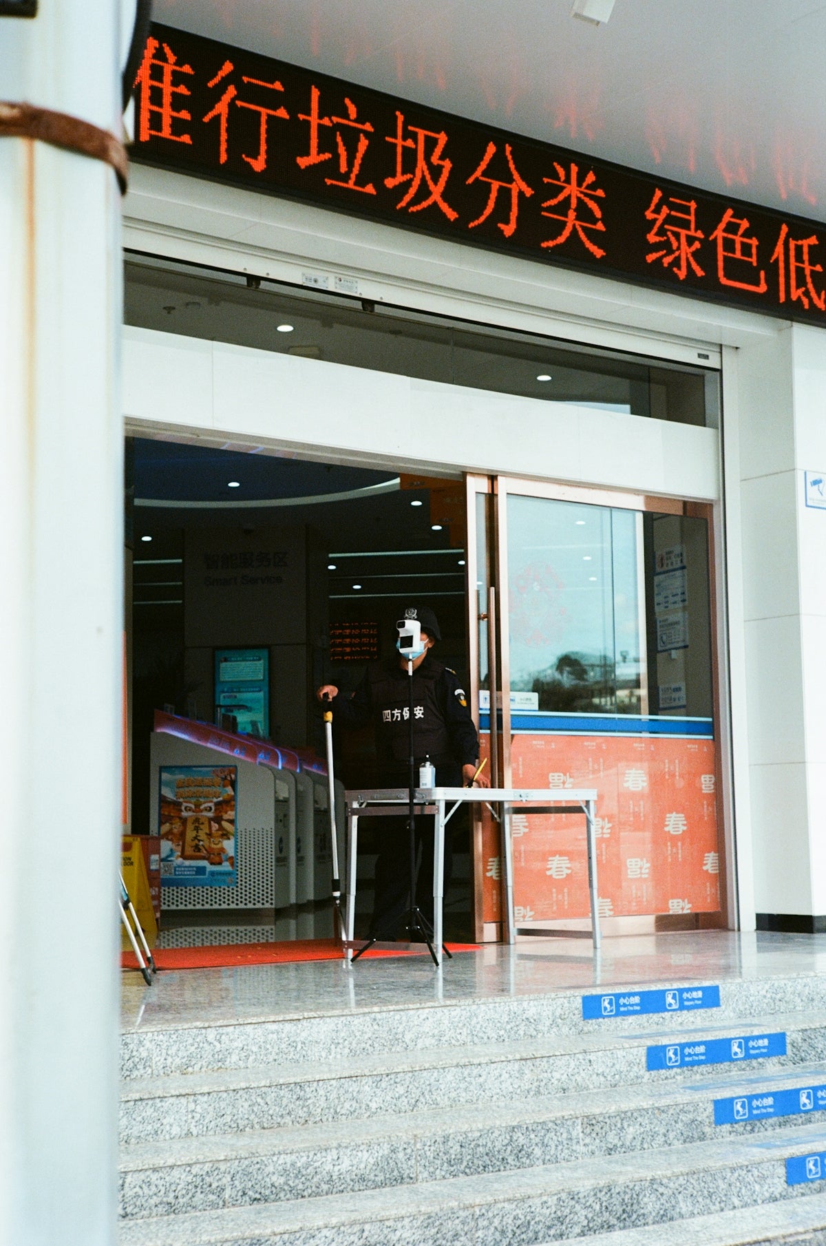 A masked security guard stands by an entrance.