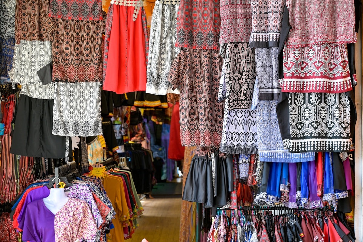 Clothes are displayed for sale in a colorful shop.