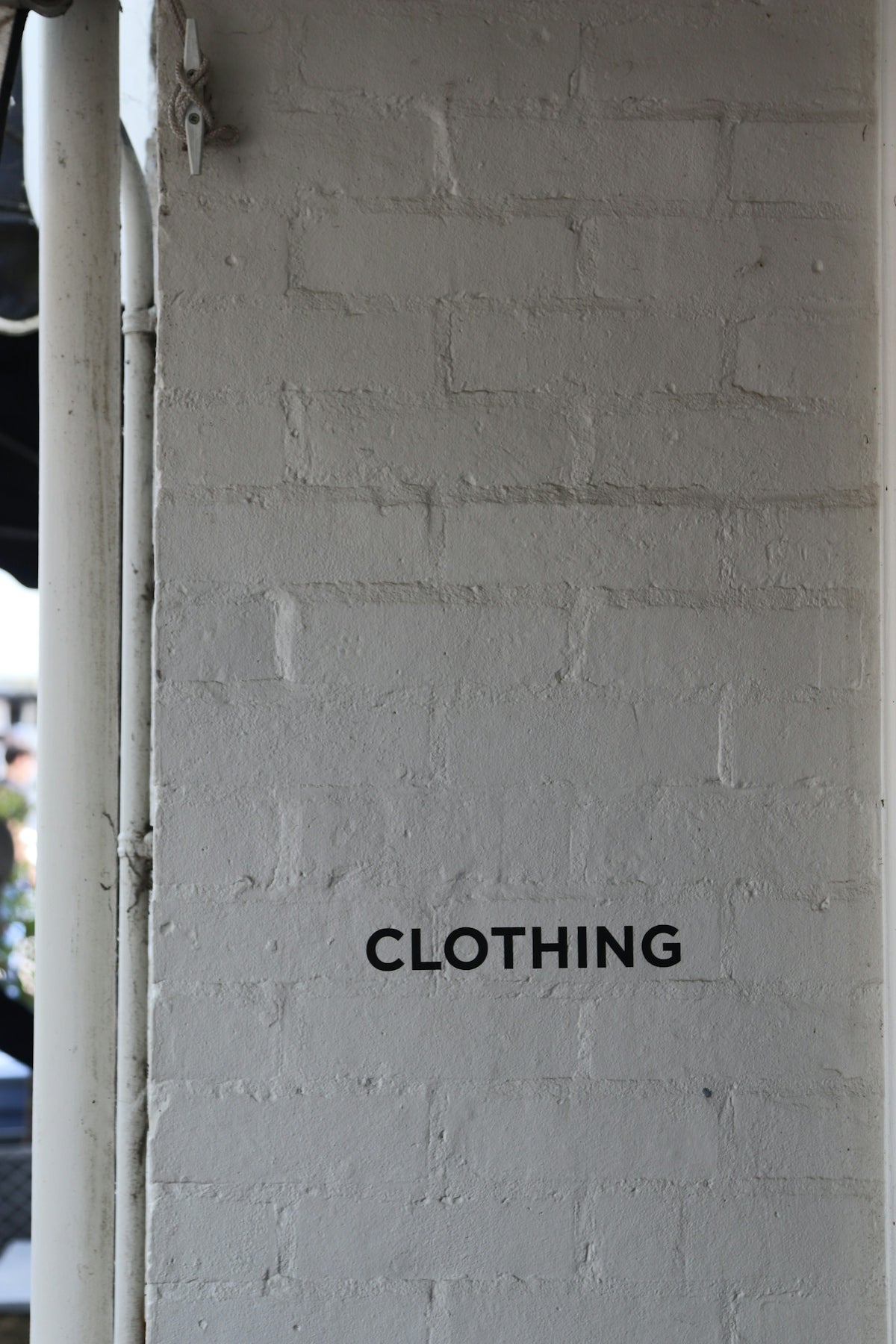 The word clothing is on a brick wall.