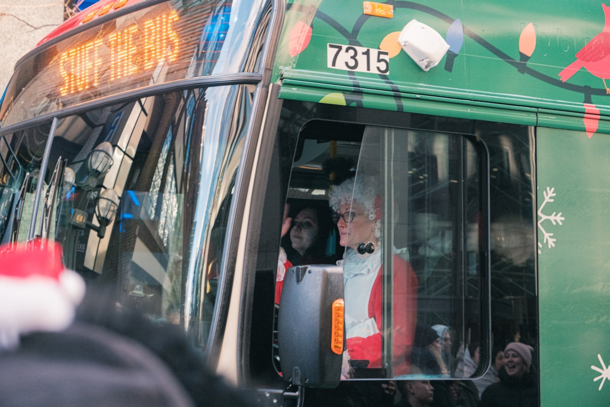 People in festive holiday attire on a decorated bus.